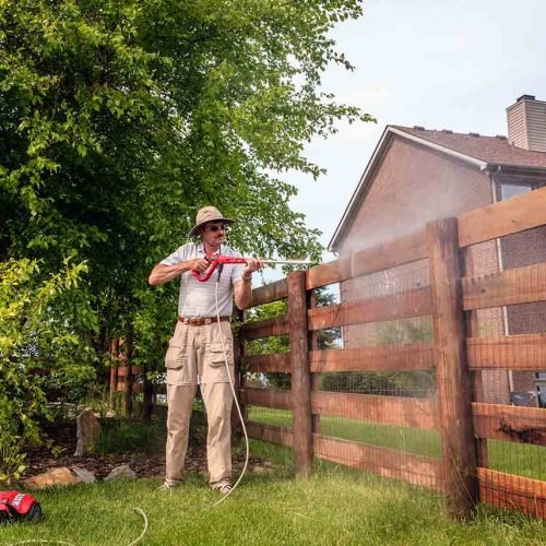 man-cleaning-a-wooden-fence-with-an-electric-power-washer